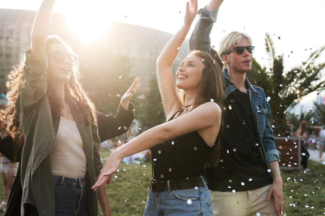 Młodzi przyjaciele tańczą wśród konfetti na plenerowym festiwalu